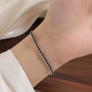 Detail of a minimalist gold bead red string bracelet on wrist with elegant silk background