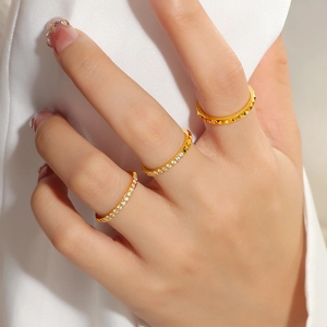 Dreiteiliges goldenes Titanstahl-Ring-Set mit Kristallen und Nietentextur am Finger