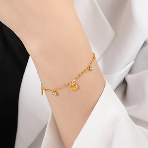 Bracelet coquillage doré avec breloques en zircone sur un poignet de femme élégant