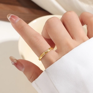 Elegante gouden gedraaide ring met zirkonia inleg op de wijsvinger van een model