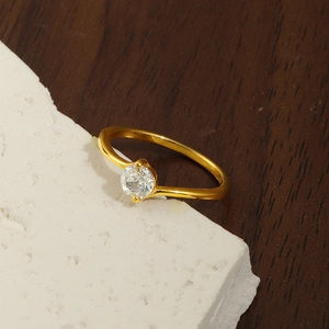 Detailansicht eines vergoldeten Titanrings mit vierzackigem runden Zirkoniastein
