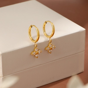 Pendientes de aro con trébol dorado y circonitas brillantes en un joyero de lujo