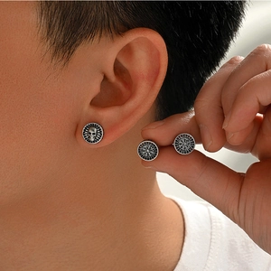 Close-up of vintage silver skull and Viking compass stud earrings for men punk style