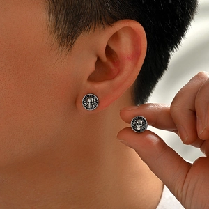 Detailed close-up of gothic skull stud earrings with engraved radial edge pattern