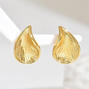 Detalle de pendientes dorados en forma de gota con grabado de textura de metal
