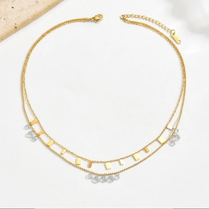 Détail d'un collier double rang doré avec pendentifs rectangulaires et pierres de zircon