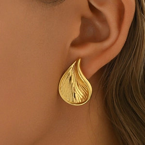 Primer plano de pendiente de gota dorado con textura radiante usado por una modelo