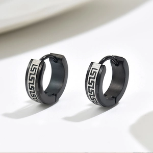 Detalle de pendientes en acero inoxidable negro con grabado de greca plateada