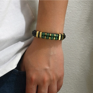 Détail du bracelet tressé en cuir noir pour homme avec perles de pierre verte et métal doré