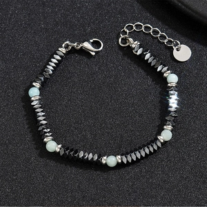 Detailed macro of beaded bracelet with hematite stones and blue beads on black sand