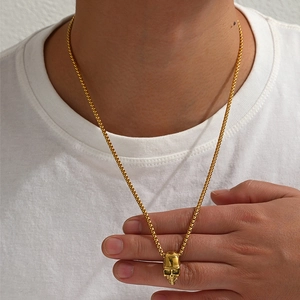 Détail d'un pendentif crâne doré avec chaîne gourmette porté par un mannequin homme