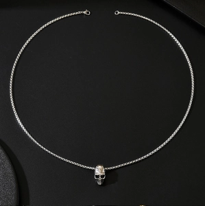 Vue détaillée du pendentif tête de mort argenté avec chaîne box sur fond texturé noir