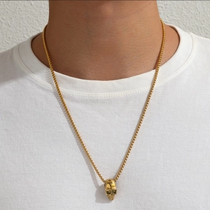 Détail d'un collier pour homme avec pendentif crâne doré et chaîne en boîte