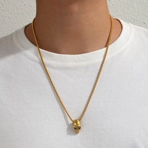 Collier à pendentif tête de mort doré sur chaîne carrée porté par un mannequin punk