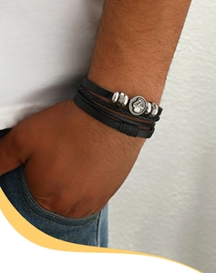 Men's multi-layer black leather bracelet with silver skull charm on a model's wrist