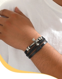 Detail of multi-layer leather bracelet with skull and axe charms in punk style