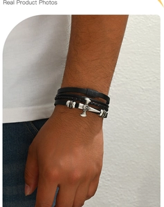 Close-up of a multi-layer black leather woven bracelet with a silver cross charm