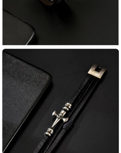 Macro detail of men's leather braided bracelet with silver skull cross and metal clasp