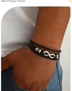Detail of men's black braided leather bracelet featuring a silver infinity charm