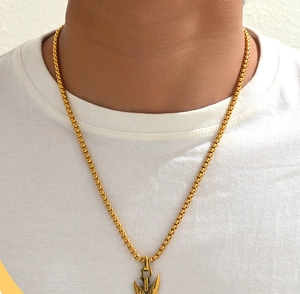 Primer plano de una cadena dorada con colgante de lanza sobre una camiseta blanca