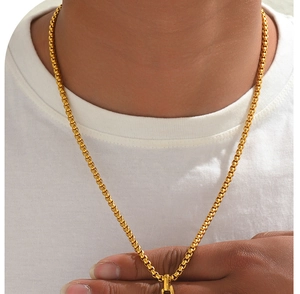 Primer plano de un collar de cadena box dorada masculina en un modelo con textura metálica