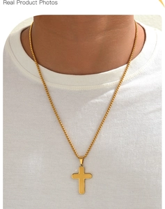 Detailed view of a gold cross pendant and box chain necklace worn by a model