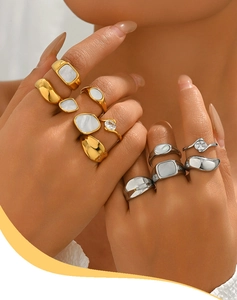 Detail shot of dual-tone irregular rings with shell inlays and zircon on model's hand