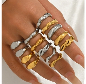 Dettaglio di anelli minimalisti in acciaio inossidabile oro e argento con design a onde
