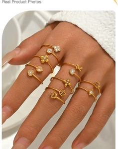 Nahaufnahme von goldenen Blumen- und Herzringen mit Zirkonia auf der Hand des Models