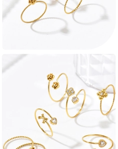 Detailansicht goldener Stapelringe mit funkelnden Blumen-, Herz- und Schleifenmotiven