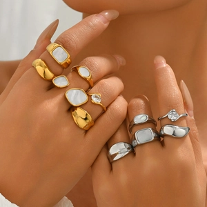 Two-tone stainless steel rings with mother of pearl and zircon details on hand