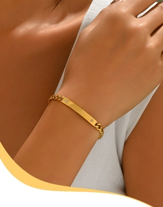 Detailed view of a gold-plated Cuban chain bracelet with a smooth bar on a woman's wrist