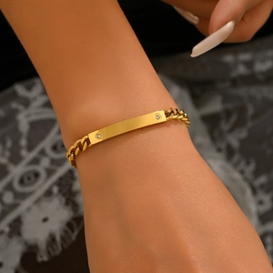 Polished gold stainless steel Cuban link bracelet with rhinestone ID plate on wrist