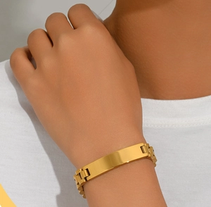 Detail of a gold titanium steel link bracelet with a rectangular engraving plate on wrist
