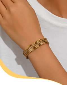 Détail d'un large bracelet maille épi dorée porté au poignet pour un style élégant