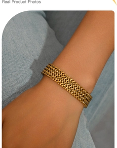 Gros plan d'un bracelet tissé à trois couches en acier titane doré sur fond de jean bleu