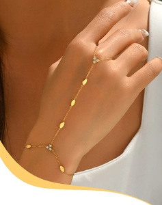 Dettaglio di un elegante bracciale ad anello dorato con dischi metallici lisci e zirconi lucidi