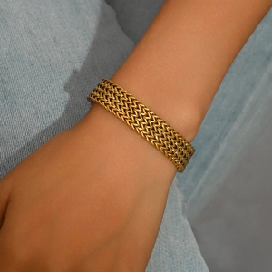 Bracelet chaîne tressée plate en acier titane doré porté au poignet d'un mannequin