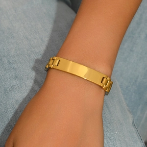 Classic gold titanium steel link bracelet with flat rectangular plate on denim background