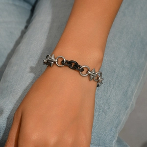 Bracciale ad anelli d'argento e maglie nere con punte metalliche su fondo denim