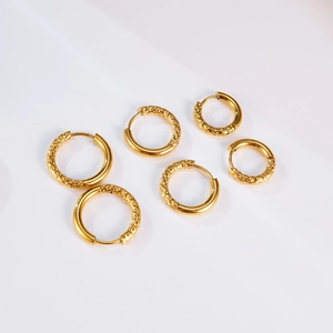 Primer plano de tres pares de pendientes de aro dorados con textura martillada