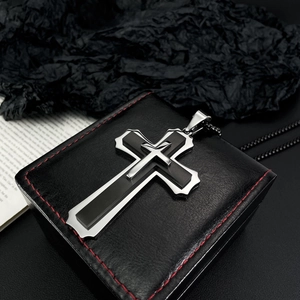Detailweergave van een dubbellaagse kruishanger in zwart en zilver aan een kralenketting