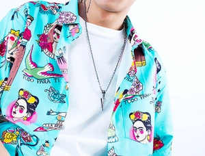 Close-up of arrow pendant necklace on model wearing blue printed shirt and white t-shirt