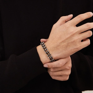 Detail eines Herrenhandgelenks mit industriellem Edelstahl-Fahrradkettenarmband in Schwarz