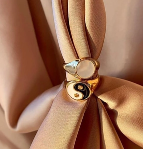 Gold plated stainless steel rings with yin yang and white shell inlays on silk fabric