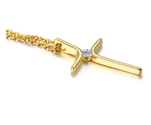 Makroaufnahme der goldenen Kreuzkette mit einem funkelnden Zirkonstein in der Mitte