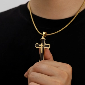 Detail of a vintage double-layer cross pendant with black core and gold-tone wheat chain