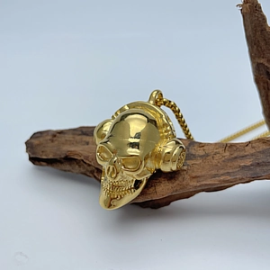 Makro-Detail des goldenen Totenkopf-Anhängers mit Kopfhörern auf Vintage-Holz