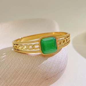 Macro shot of gold hollow chain bracelet featuring a square green cat-eye gemstone