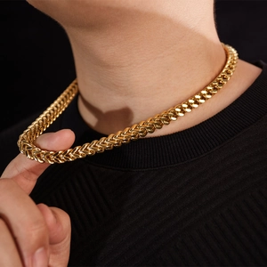 Close-up of gold plated thick Franco link chain necklace on a male model with black shirt